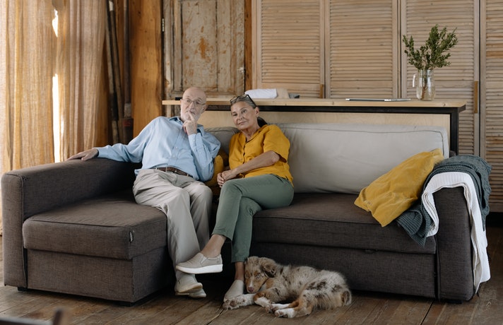 سگ پیر خوابیده در کنار پیر زن و پیرمردی که روی مبل نشسته اند