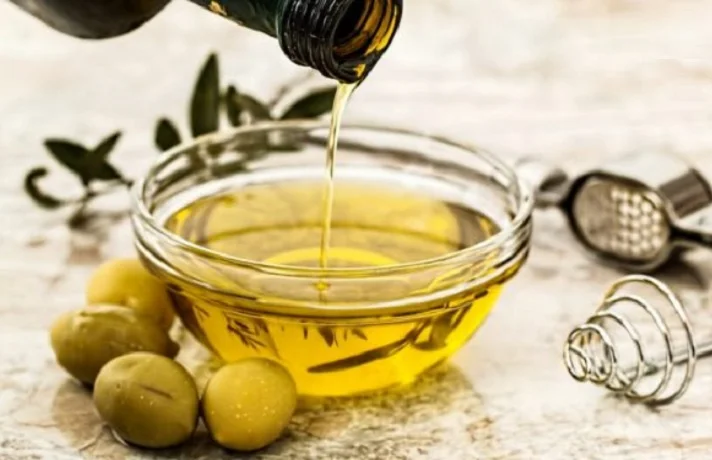 روغن زیتون را از بطری به داخل کاسه می ریزد