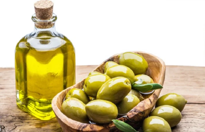 روغن زیتون سگ در یک بطری در کنار یک کاسه پر از زیتون